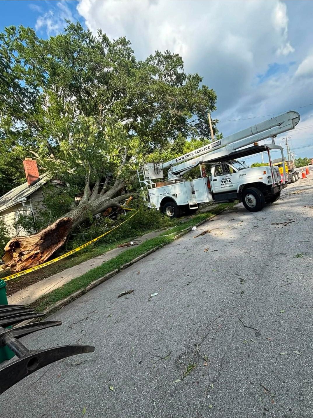 A tree down on a house with the bucket truck on the street